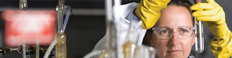 Femme portant des lunettes de sécurité en pleine expérience de laboratoire